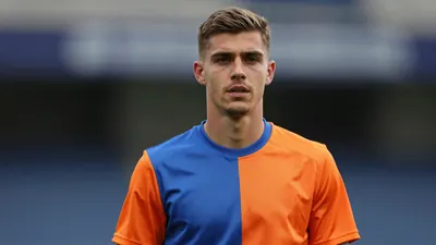 A determined Eastleigh midfielder, early twenties, athletic build, waist-up shot, face sharp and centered, wearing an...